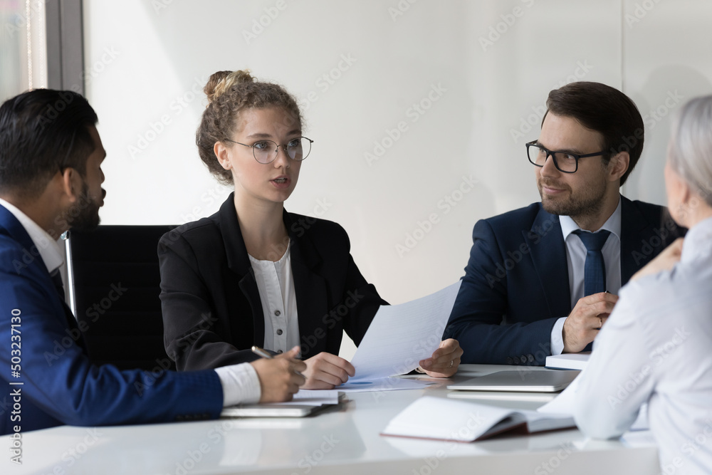 Serious young business professional woman speaking at corporate meeting, analyzing paper document, giving expertise, consultation. Female boss, team leader instructing group Serious young business professional woman speaking at corporate meeting, analyzing paper document, giving expertise, consultation. Female boss, team leader instructing group