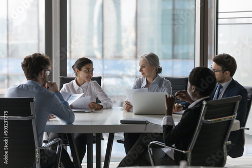 Multiethnic business team working together, brainstorming, discussing project, talking at table in meeting room. Startup managers, investors analyzing marketing data, stats report