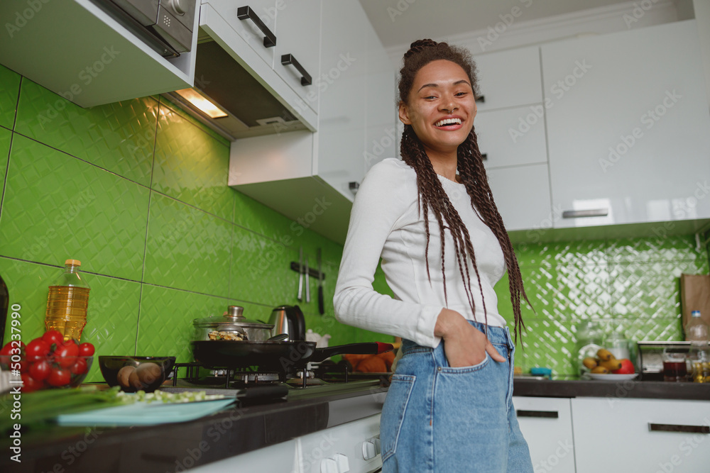 Stylish happy young woman smiling to camera in the kitchen, housewife preparing food Stylish happy young woman smiling to camera in the kitchen, housewife preparing food