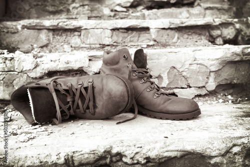 Fotografija A pair of old worn brown leather shoes with laces on an old brick porch
