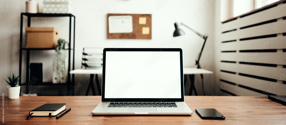 Blank empty screen on laptop on the table at loft workplace. Mockup