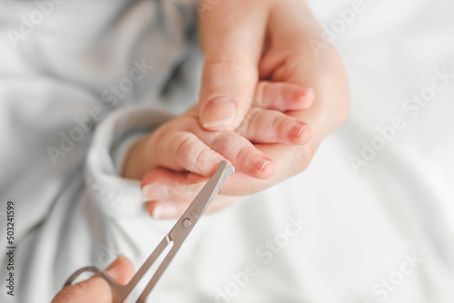 mom cuts baby's fingernails with special children's scissors. close up. manicure for newborns. white background