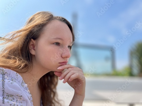 the face of a girl who sits against the backdrop of the Eiffel Tower she is thoughtfully relaxed beautiful there is a place for text for advertising. High quality photo