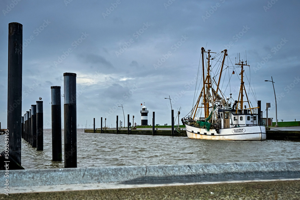 Krabbenkutter liegt im Hafen von Wremen vor dem Leuchtturm Kleiner Preuße an der Wurster Nordseeküste.