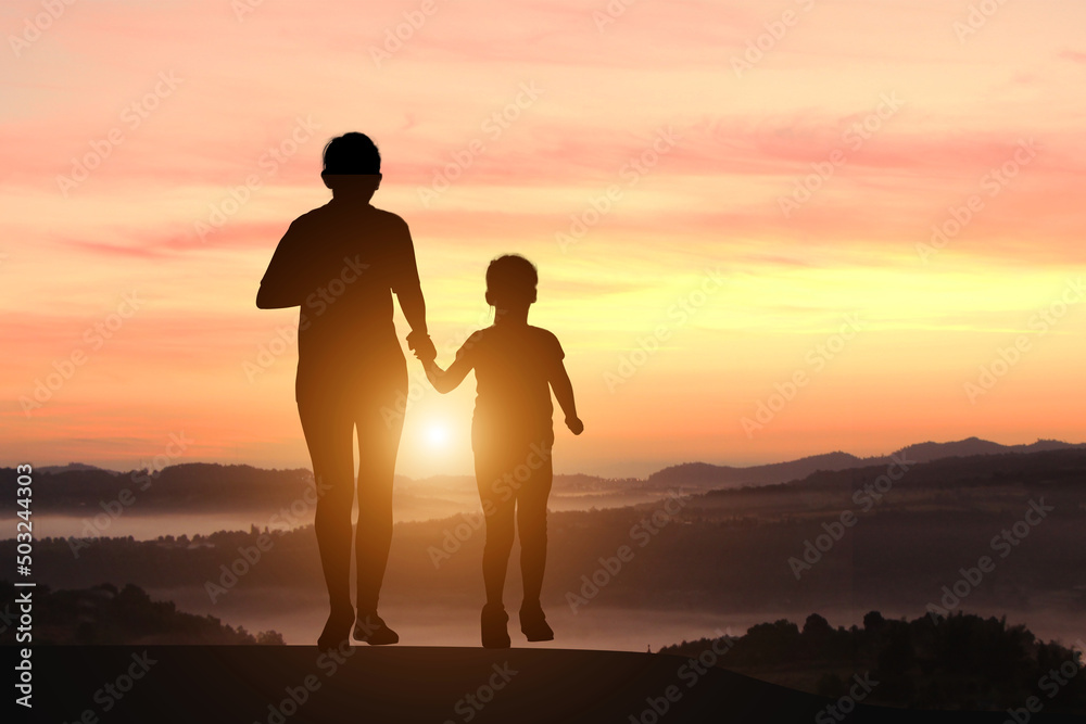 Silhouette of mother and son jogging at sunset