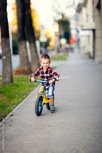Stylish boy ride on balance bike on sidewalk in city © natalialeb
