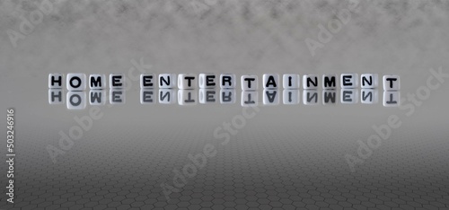 home entertainment word or concept represented by black and white letter cubes on a grey horizon background stretching to infinity
