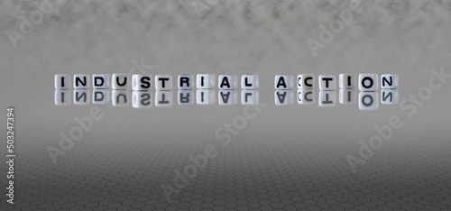 industrial action word or concept represented by black and white letter cubes on a grey horizon background stretching to infinity