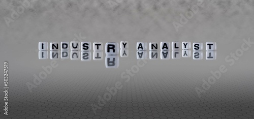industry analyst word or concept represented by black and white letter cubes on a grey horizon background stretching to infinity