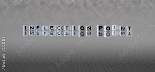 inflection point word or concept represented by black and white letter cubes on a grey horizon background stretching to infinity