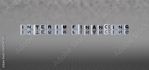 interim financing word or concept represented by black and white letter cubes on a grey horizon background stretching to infinity photo