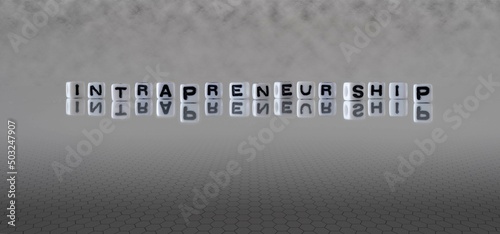 intrapreneurship word or concept represented by black and white letter cubes on a grey horizon background stretching to infinity photo