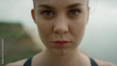 Closeup woman opening eyes standing on coast hill. Girl doing breathing exercise photo
