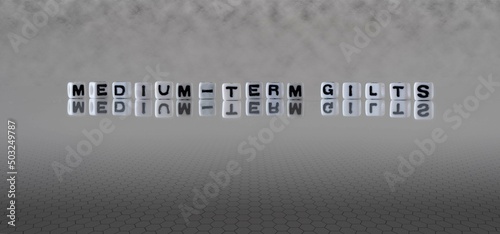 medium term gilts word or concept represented by black and white letter cubes on a grey horizon background stretching to infinity
