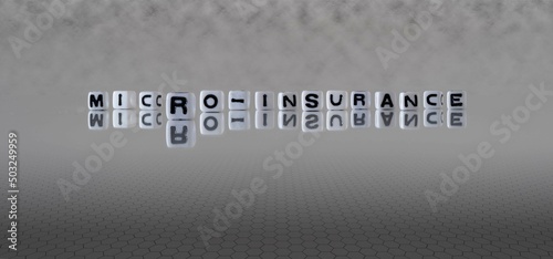 micro insurance word or concept represented by black and white letter cubes on a grey horizon background stretching to infinity photo