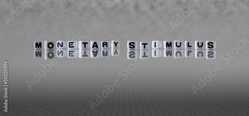 monetary stimulus word or concept represented by black and white letter cubes on a grey horizon background stretching to infinity