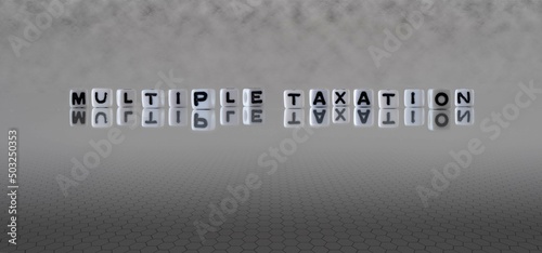 multiple taxation word or concept represented by black and white letter cubes on a grey horizon background stretching to infinity