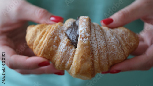 Person holds fresh tasty croissant with chocolate