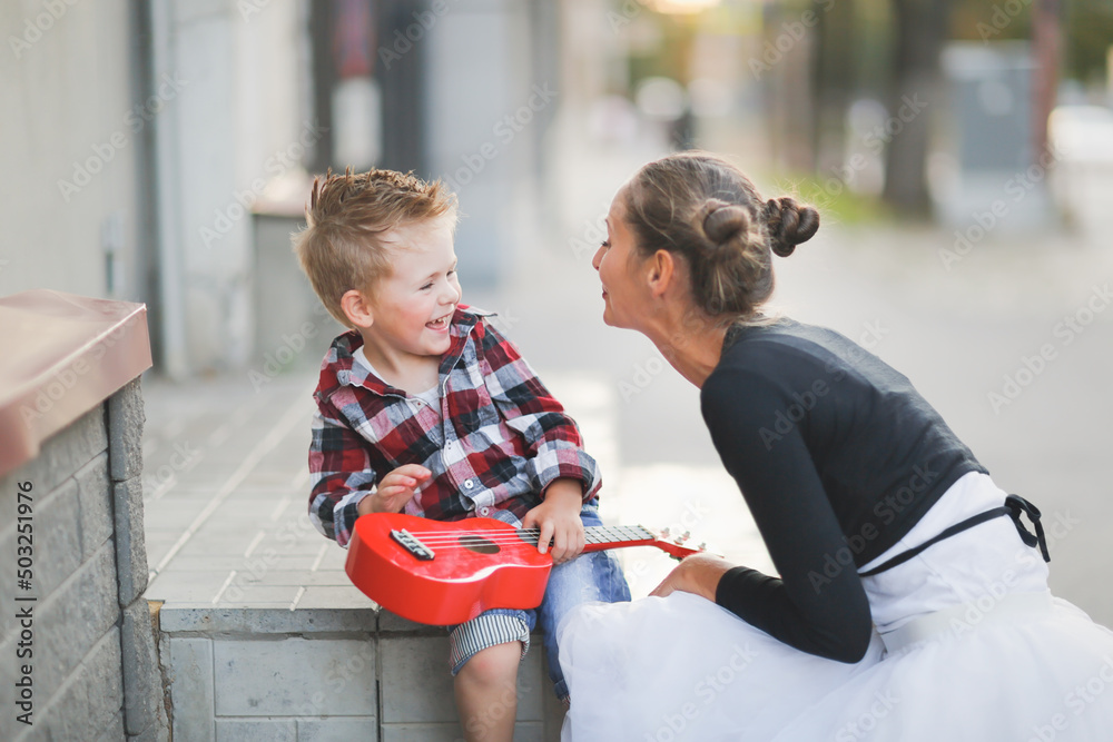 mother and son hugging playing ukulele outside mother and son hugging playing ukulele outside