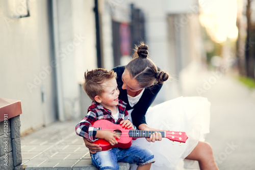 mother and son hugging playing ukulele outside
