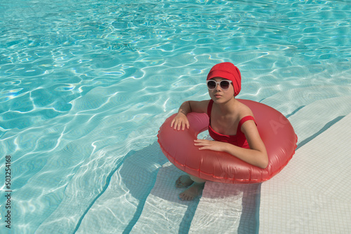 young woman in vintage red swim suit and bathing cap in swimming pool in summer sun