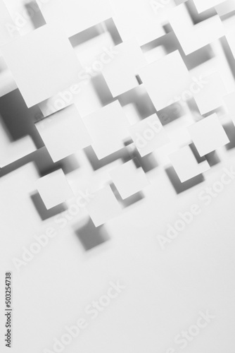 White abstract background - geometric pattern of flying rhombuses in bright light with soft contrast grey shadows as border, copy space, top view. Simple minimal backdrop for advertising, design.