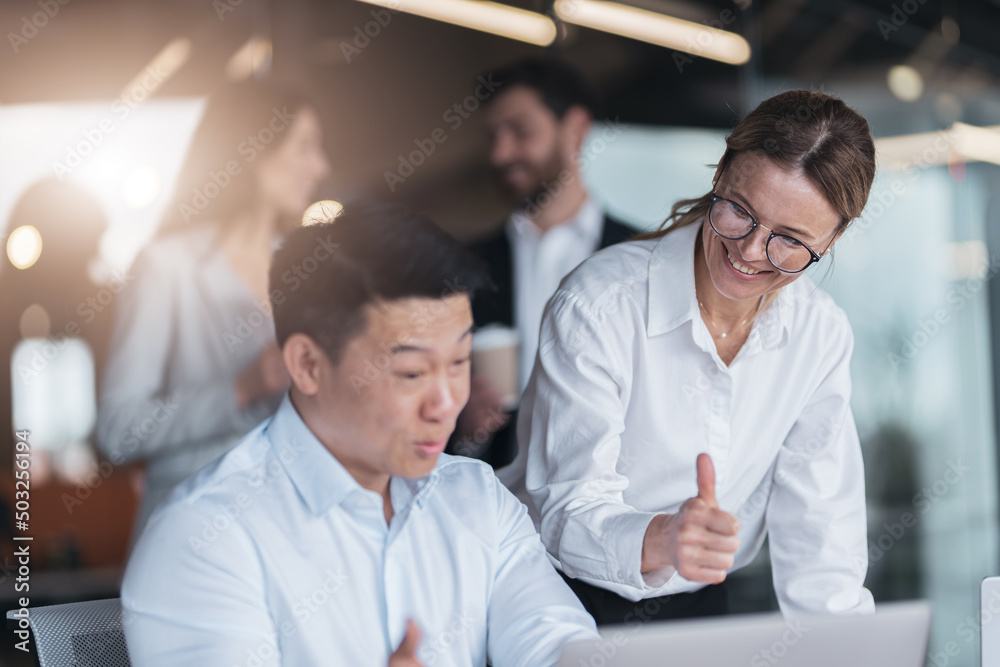 Focused mature female employee discussing project, showing presentation to skilled team leader. 