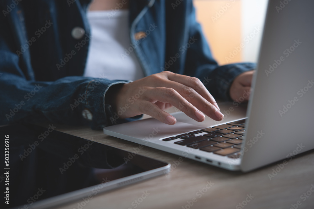 Closeup woman working, hands typing on laptop computer on wooden desk at office.