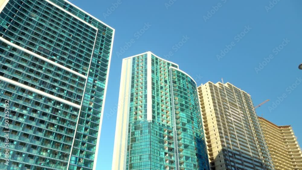 View from below of modern skyscrapers in business district against blue sky. Looking at business buildings in city center. Panorama camera view of bottom. Mirror fasade of creation. Business center. View from below of modern skyscrapers in business district against blue sky. Looking at business buildings in city center. Panorama camera view of bottom. Mirror fasade of creation. Business center.