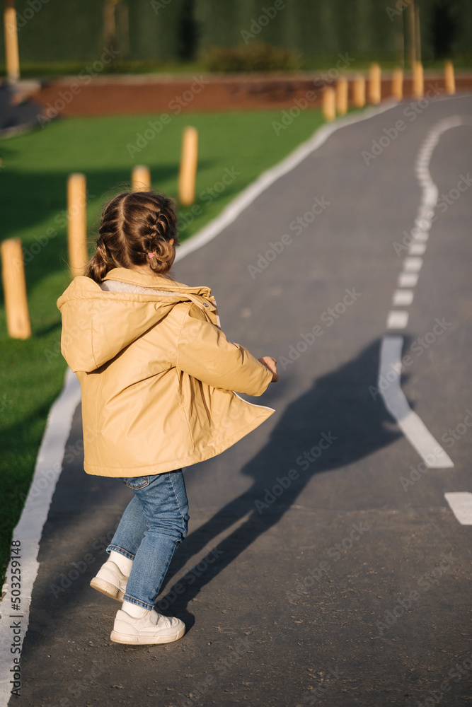 Back view of little girl walking in little kids city. Toy city for children outdoors. Road for walking Back view of little girl walking in little kids city. Toy city for children outdoors. Road for walking