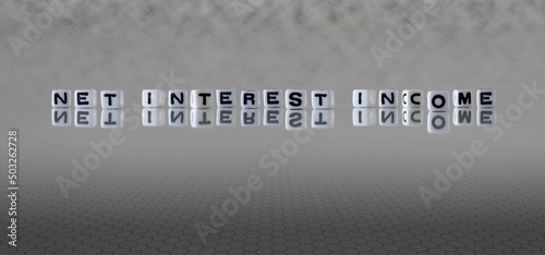 net interest income word or concept represented by black and white letter cubes on a grey horizon background stretching to infinity