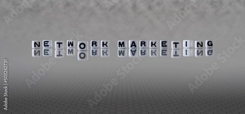 network marketing word or concept represented by black and white letter cubes on a grey horizon background stretching to infinity