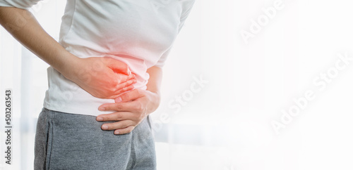 Young woman put her hand on her stomach because she had a very bad stomachache. menstrual pain, gastritis or diarrhoea. Healthcare medical concept.