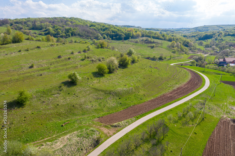 Aerial view of village road passing near an agricultural field
