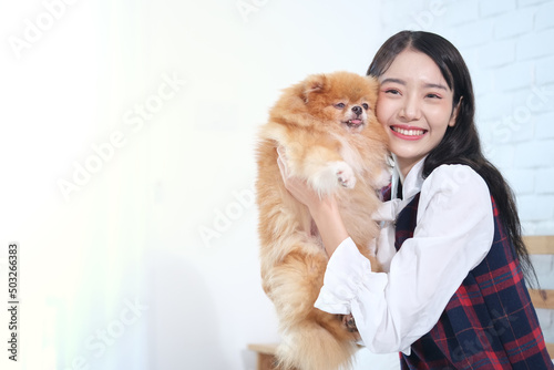 Beautiful Asian woman holding a Pomeranian dog. and play with tenderness and a lovely smile, Copy space
