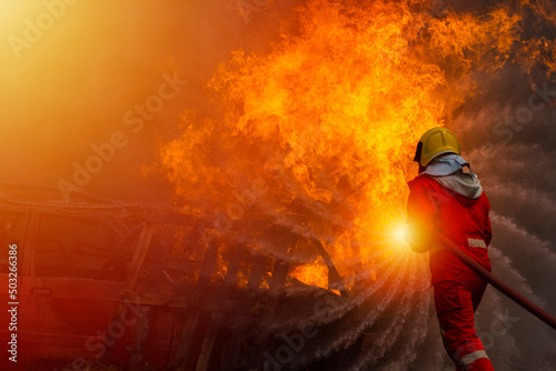 A firefighter in suit and helmet is extinguishing that the fire is burning, Copy space.
