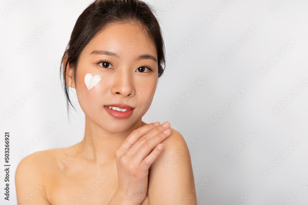 Asian lady posing with heart shaped cream on cheek Asian lady posing with heart shaped cream on cheek