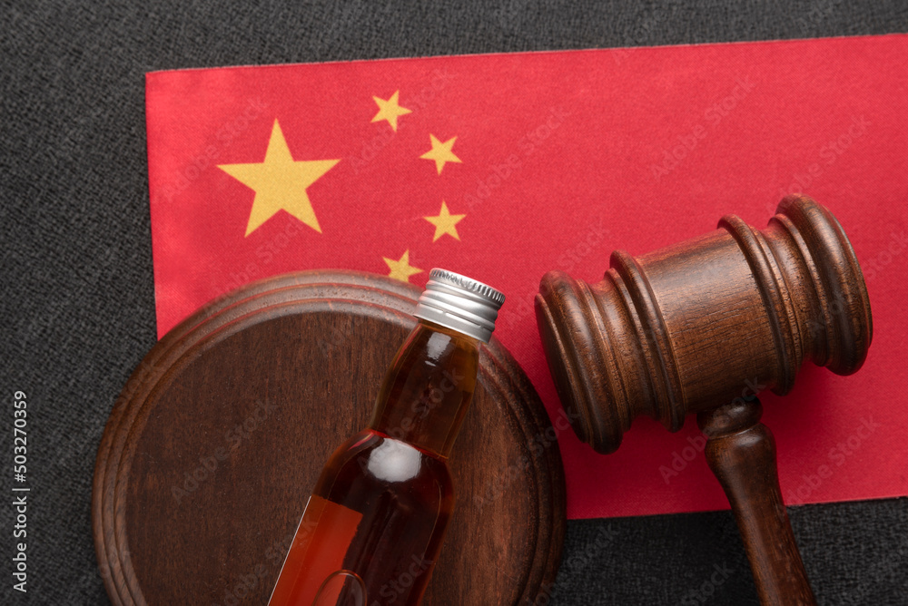Judges Gavel and bottle of alcohol on China flag. Alcohol legislation. Law and order concept. Alcohol problems in China.