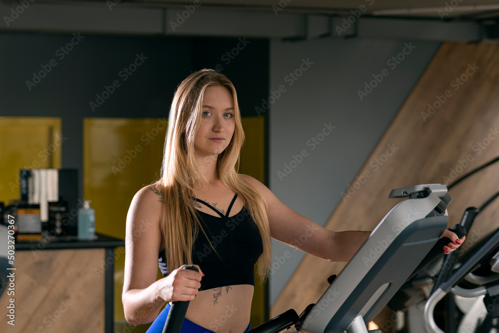 Portrait of sexy young woman trains in the gym. Aerobic exercise on the Elliptical Trainer orbitrek. Portrait of sexy young woman trains in the gym. Aerobic exercise on the Elliptical Trainer orbitrek.