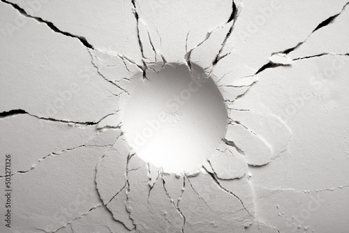 White powder surface with cracks and a round crater. Crater in black and white.