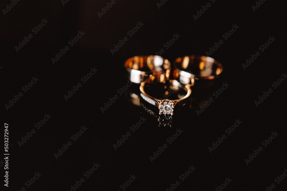 Diamond rings on black Chic wedding rings with diamonds on a black background with a light color effect.blue background with flower. Diamond rings on black Chic wedding rings with diamonds on a black background with a light color effect.blue background with flower.