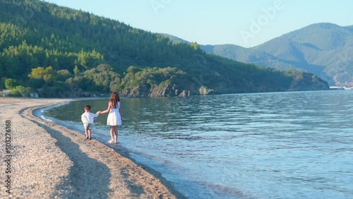 Children run forward along the beach. Brother and sister walking along the seashore on a sunny day. Concept of a beach holiday for young children