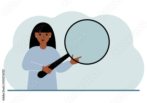 A woman holds a large loupe or magnifying glass in his hands.