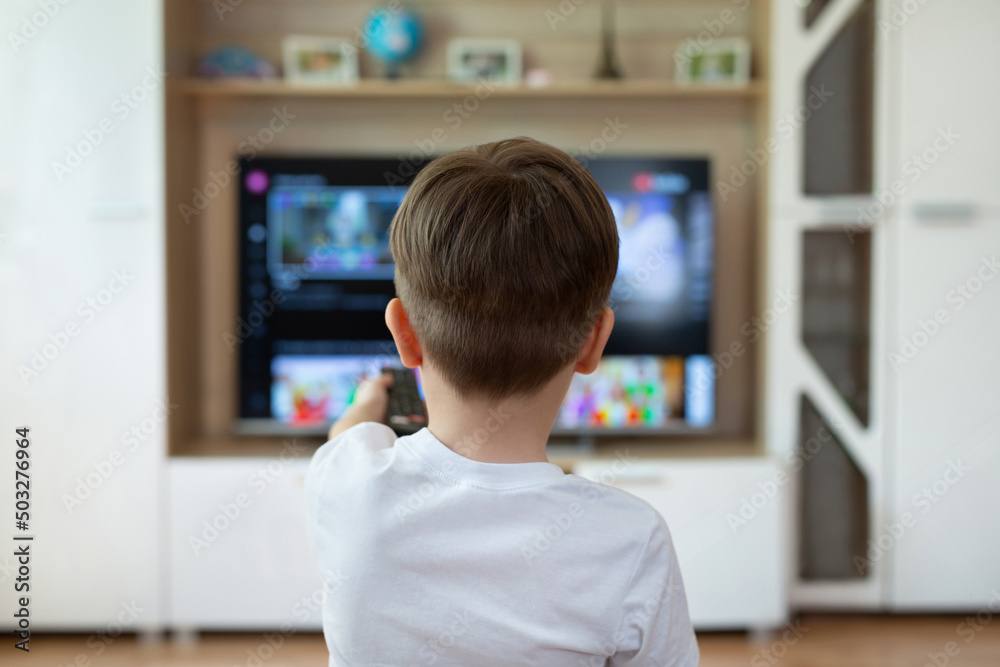 Little boy is sitting on the couch and switching TV channels Little boy is sitting on the couch and switching TV channels