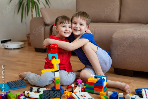 Children play with colorful toys with a constructor on the floor and hug