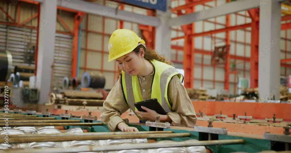 Asian female factory worker in safety clothing using digital tablet Asian female factory worker in safety clothing using digital tablet