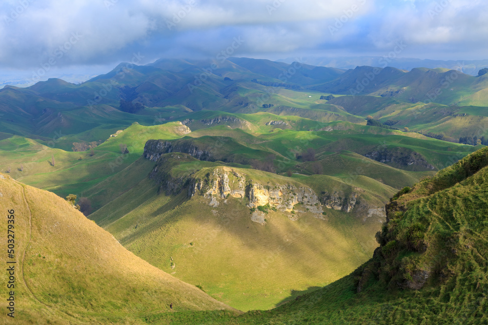 Obraz premium A mountain landscape seen from the top of Te Mata Peak in the Hawke's Bay region, New Zealand. The tiny figure of a hiker is just visible at the bottom