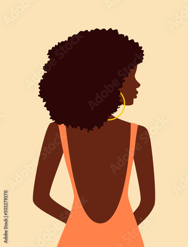Beautiful african woman with curly hair in peach dress with open back looking over her shoulder
