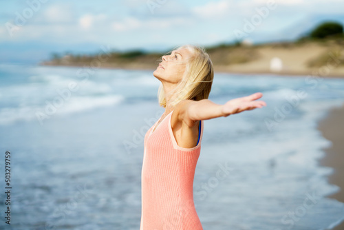 Beautiful mature woman opening her arms on a beautiful beach, enjoying her free time