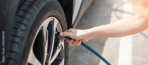 hand inflating tires of vehicle, checking air pressure and filling air on car wheel at gas station. self service, maintenance and safety transportation concept photo